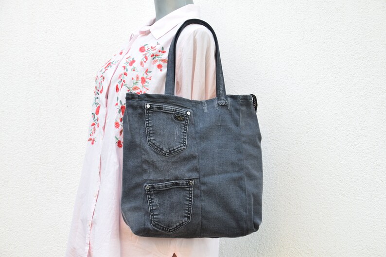 May include: A gray denim tote bag with multiple pockets. The bag has black handles and a zipper closure.