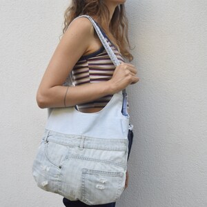 May include: A light blue denim tote bag with a white fabric lining. The bag has a long strap and is made from recycled denim.