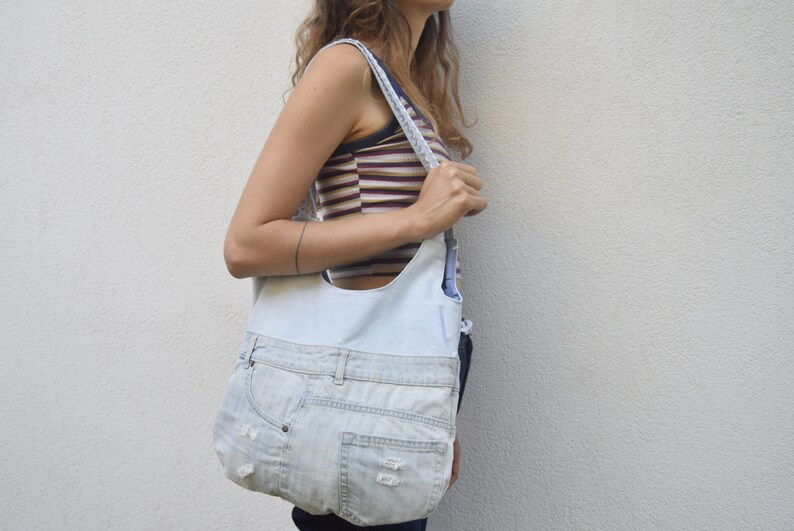 May include: A light blue denim tote bag with a white fabric lining. The bag has a long strap and is made from recycled denim.