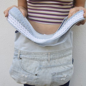 May include: A light blue denim tote bag with a white lace trim. The bag is made from recycled denim and has a spacious interior.