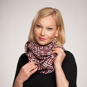 Könnte beinhalten: Eine Frau trägt einen schwarzen Rollkragenpullover mit einem burgunderfarbenen und weißen gemusterten Infinity-Schal.