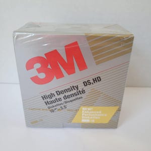 May include: A sealed box of 3M High Density 3.5" diskettes. The box is silver with gold diagonal lines and the 3M logo in red. Text includes "High Density DS, HD" and "Enhanced Performance Diskettes".