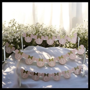 Puede incluir: Bandera rosa y dorada con tem&aacute;tica de Minnie Mouse que deletrea "HAPPY BIRTHDAY". Cada letra est&aacute; en una cabeza de rat&oacute;n rosa con un lazo dorado. Se adjuntan cintas blancas para colgar. Ideal para una fiesta de cumplea&ntilde;os.