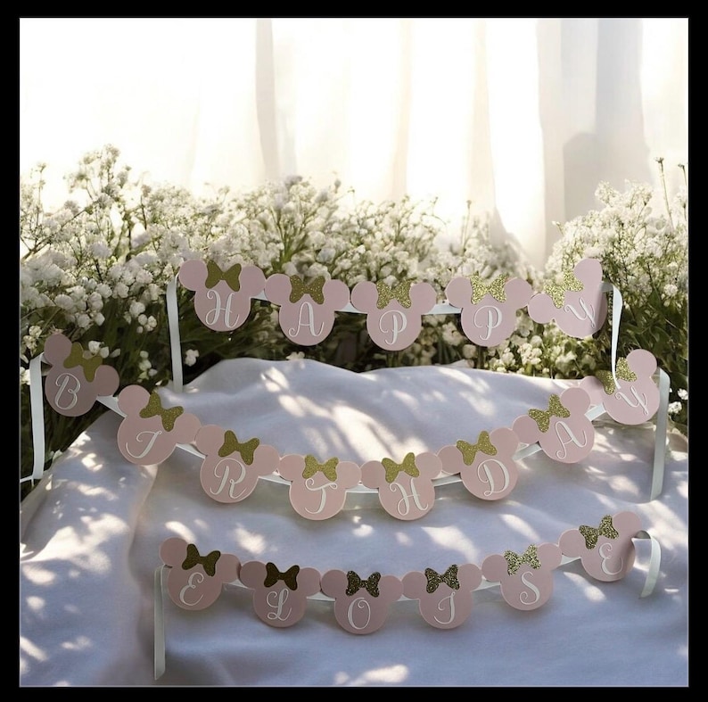 Puede incluir: Bandera rosa y dorada con tem&aacute;tica de Minnie Mouse que deletrea "HAPPY BIRTHDAY". Cada letra est&aacute; en una cabeza de rat&oacute;n rosa con un lazo dorado. Se adjuntan cintas blancas para colgar. Ideal para una fiesta de cumplea&ntilde;os.