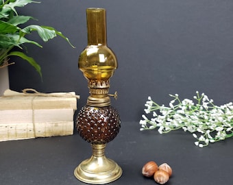 May include: An antique oil lamp with a brown glass globe and a brass base. The lamp has a textured, bubble-like pattern on the lower globe and a smooth, cylindrical top. The lamp is approximately 20 cm tall.
