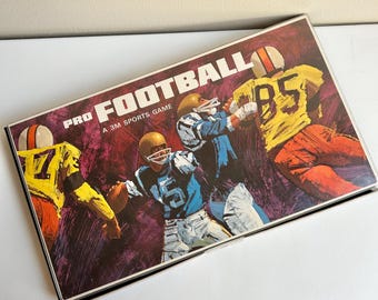 May include: Vintage "Pro Football" board game box. The box features illustrations of football players in action, wearing yellow, blue, and orange uniforms. The game is a 3M Sports Game.