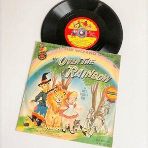 May include: A vintage record and book set featuring the song "Over the Rainbow" from the Wizard of Oz. The book cover features illustrations of Dorothy, the Scarecrow, the Tin Man, and the Cowardly Lion.