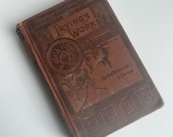 May include: A vintage brown book with gold lettering and decorative designs. The title on the cover reads "Irving's Works" with the sub-title "Rip Van Winkle & Essays".