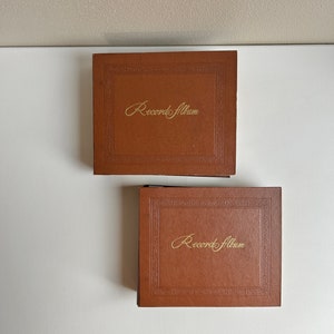May include: Two brown record albums with gold lettering that reads "Record Album".