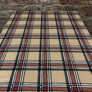 May include: A beige tablecloth with a red, black, and white plaid pattern.