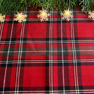 May include: Red and black plaid tablecloth with a string of white snowflake lights across the top.