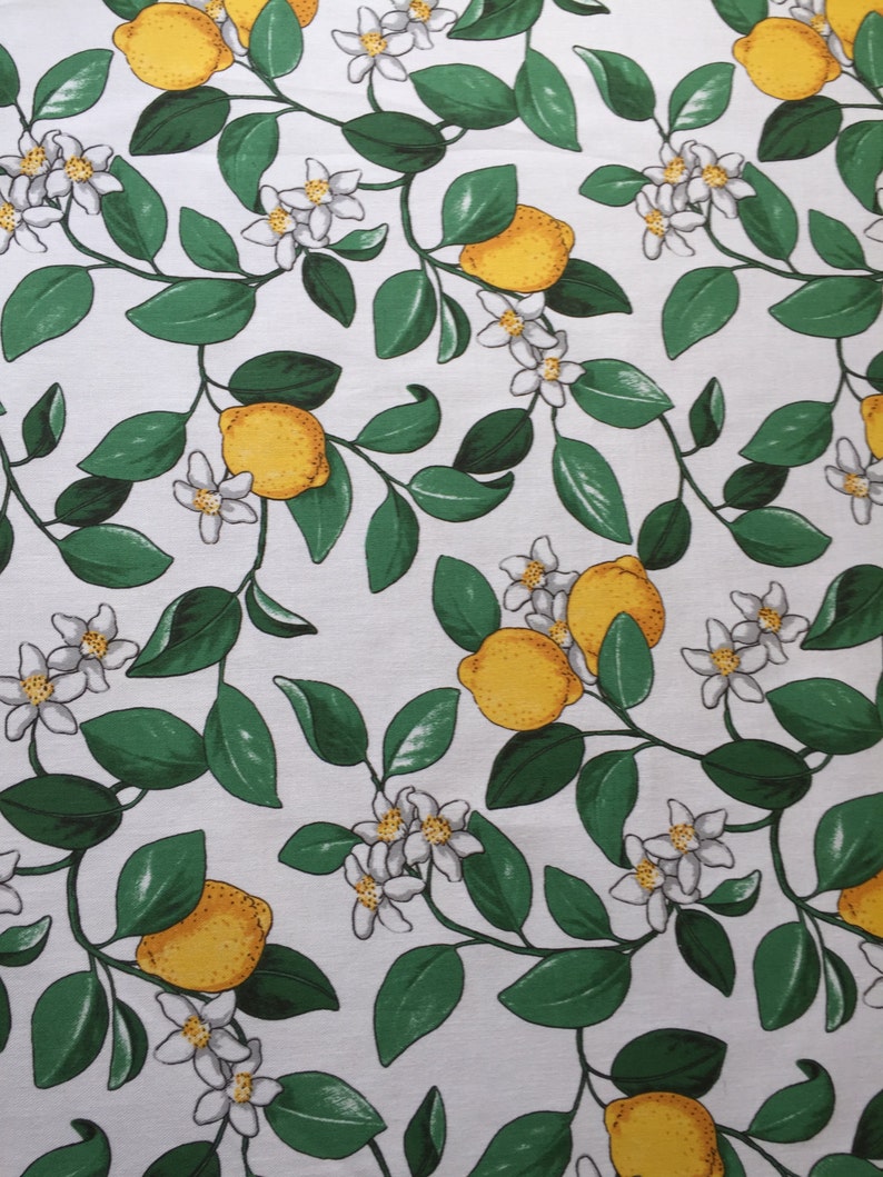 May include: White fabric with a repeating pattern of green leaves, white flowers, and yellow lemons.