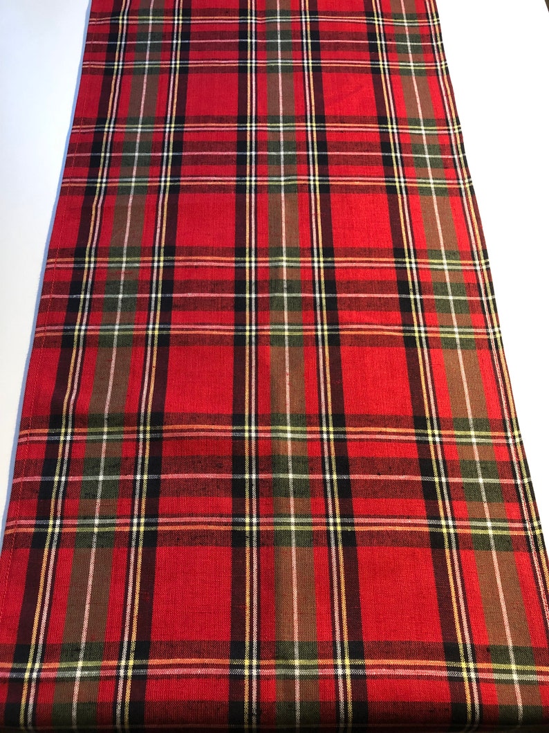 May include: Red, black, green, and white plaid table runner. The runner has a woven texture.