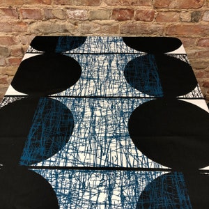 May include: Black and white fabric with a geometric pattern of overlapping circles. The circles are outlined in blue and the background is white with a blue criss-cross pattern.
