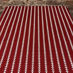 May include: Red tablecloth with a white repeating pattern of small arrows. The tablecloth is made of a woven fabric.