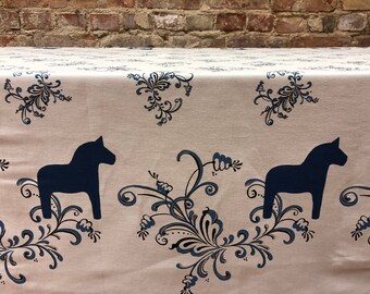 May include: Beige fabric with a repeating pattern of dark blue stylised floral designs and dark blue silhouette images of a traditional Swedish Dala horse.