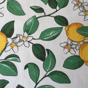 May include: White fabric with a repeating pattern of green leaves, white blossoms, and yellow lemons.