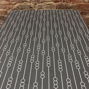 May include: A dark gray fabric with a white geometric pattern of circles connected by lines. The pattern resembles a series of abacuses.