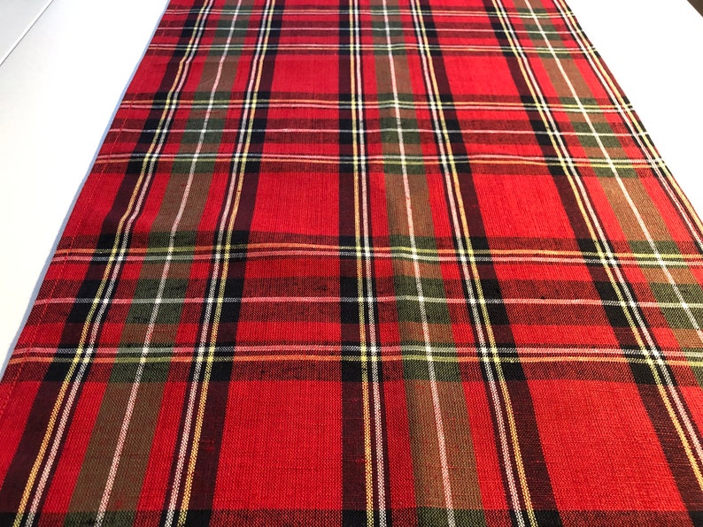 May include: Red, green, black, and white plaid table runner. The runner has a woven texture.