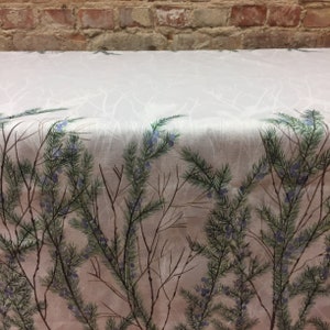 May include: A white linen tablecloth with a printed design of green branches and blue berries. The branches are arranged in a random pattern and the berries are scattered throughout the design.