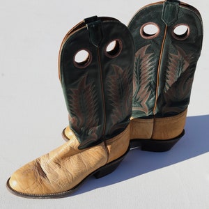 May include: A pair of tan leather cowboy boots with green leather tops and decorative stitching. The boots have a pointed toe and a stacked heel.