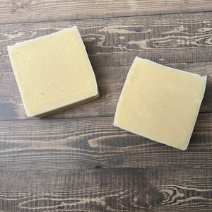 以下が含まれることがあります： 茶色の木製の表面に置かれた、薄い黄色の長方形の石鹸が2つ