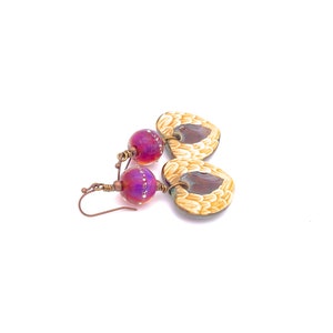 Earrings made with a heart-shaped charm featuring 2 angel wings in shades of cream with maroon in the center hang below matching maroon handmade lampwork glass beads.  Hand wrapped with copper wire.  Copper ear wires.