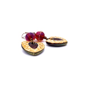 Earrings made with a heart-shaped charm featuring 2 angel wings in shades of cream with maroon in the center hang below matching maroon handmade lampwork glass beads.  Hand wrapped with copper wire.  Copper ear wires.