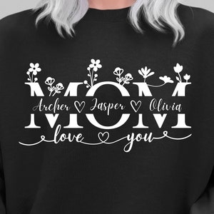May include: Black sweatshirt with white text that reads "MOM" with the names "Archer", "Jasper", and "Olivia" and the phrase "love you" with hearts.