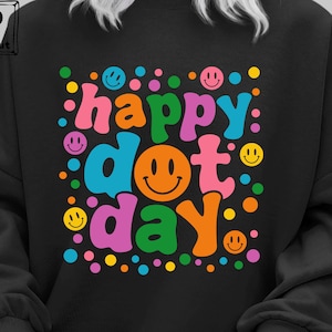 May include: Black sweatshirt with a colorful graphic design that says "happy dot day" with smiley faces and polka dots.