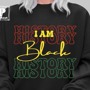 Puede incluir: Sudadera negra con el texto "I am History" en rojo y amarillo, y "Black" en amarillo con las palabras "History" en verde y amarillo repetidas debajo.