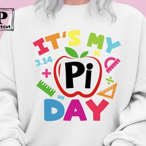 May include: White sweatshirt with a colorful graphic that says "It's My Pi Day" with a red apple with a black "Pi" inside. The graphic also includes colorful math symbols like plus signs, a ruler, and a division sign.