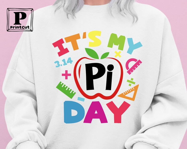 May include: White sweatshirt with a colorful graphic that says "It's My Pi Day" with a red apple with a black "Pi" inside. The graphic also includes colorful math symbols like plus signs, a ruler, and a division sign.