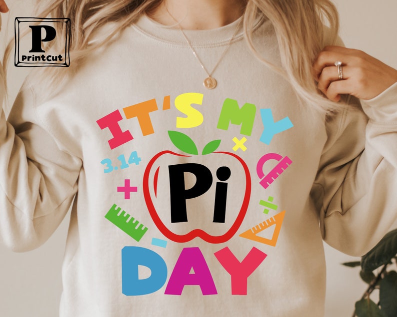 May include: A white sweatshirt with the text "It's My Pi Day" in colorful letters. The text is surrounded by various math symbols, including a red apple with a black "Pi" inside.