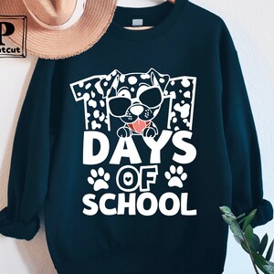 K&ouml;nnte beinhalten: Schwarzes Sweatshirt mit einer wei&szlig;en Grafik eines Dalmatiners mit Sonnenbrille und dem Text "101 Tage Schule".