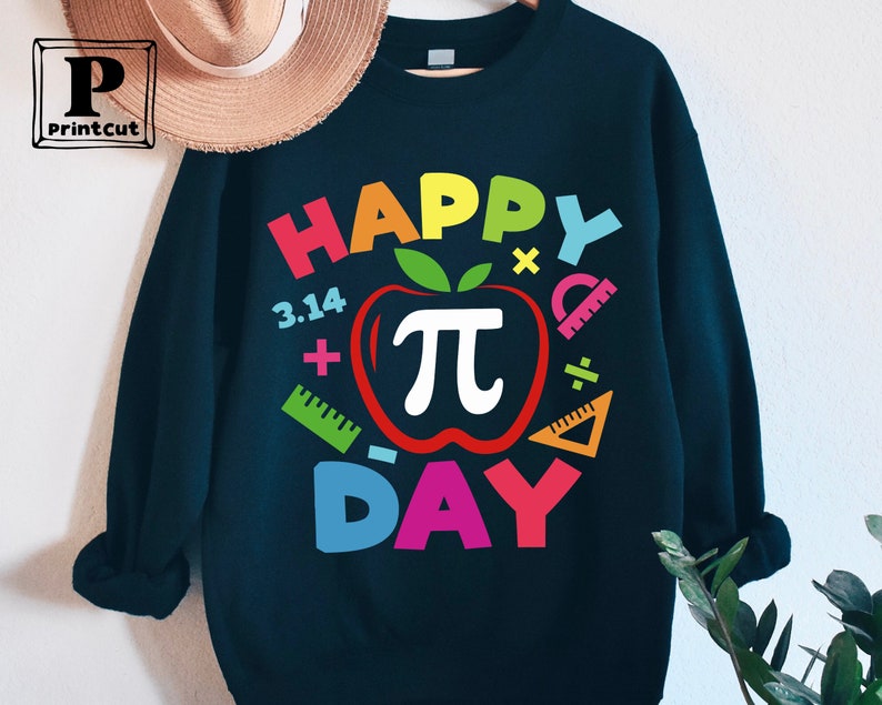 May include: A black sweatshirt with a colorful graphic design that says "Happy Pi Day" with a red apple with a white pi symbol inside. The graphic also includes colorful math symbols like plus signs, minus signs, and rulers.