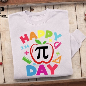 May include: White sweatshirt with a colorful graphic design that says "Happy Pi Day" with a red apple with a black pi symbol inside.