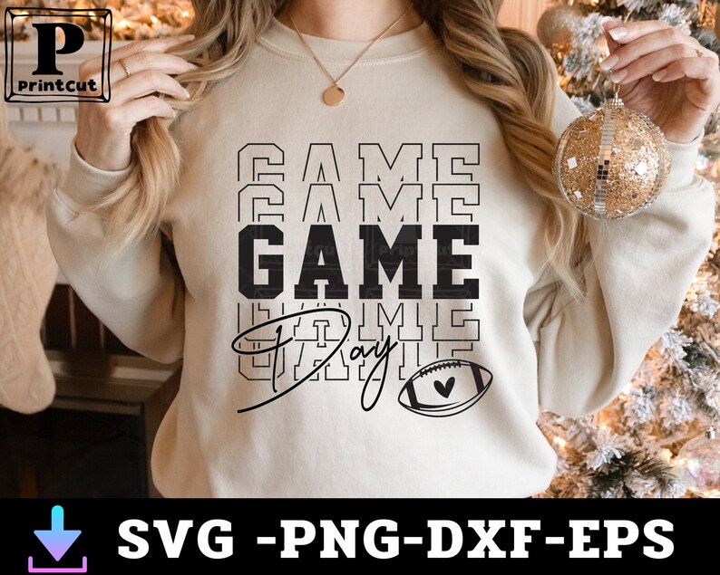 May include: A white sweatshirt with the text "GAME DAY" in black lettering. The text is stacked and repeated multiple times. A small football with a heart is below the text.