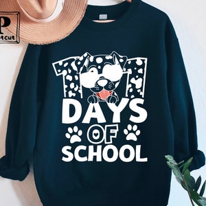K&ouml;nnte beinhalten: Schwarzes Sweatshirt mit einer wei&szlig;en Grafik eines Dalmatiners mit Sonnenbrille und dem Text "101 Tage Schule".