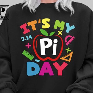 May include: Black sweatshirt with a colorful graphic design that says "It's My Pi Day" with a red apple with a white "Pi" inside.