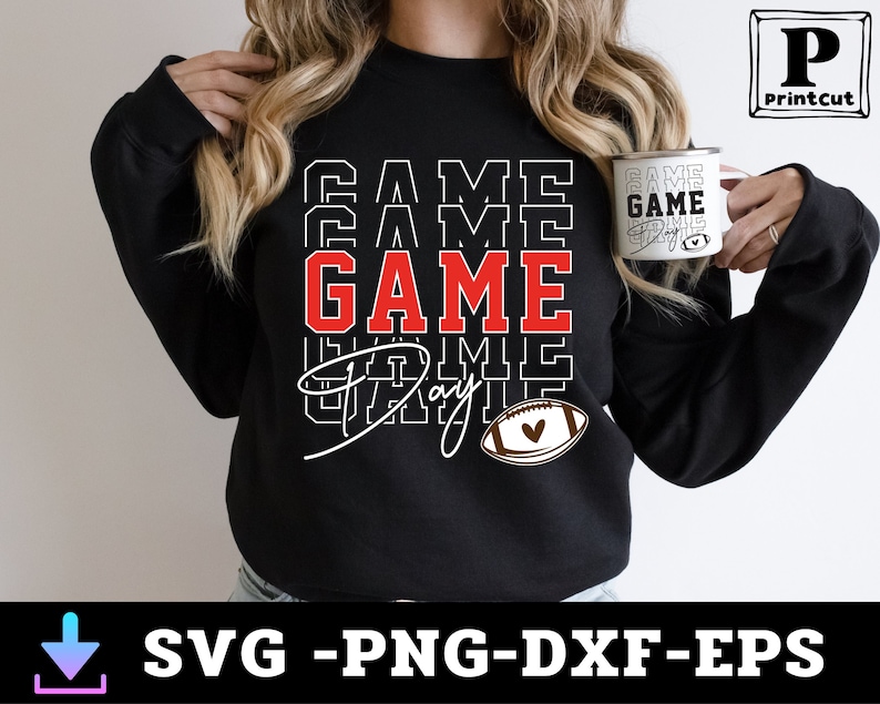 May include: Black sweatshirt with the text "GAME DAY" in white and red letters, with a football graphic and a heart. The sweatshirt is being worn by a person holding a white mug with the text "GAME DAY" on it.