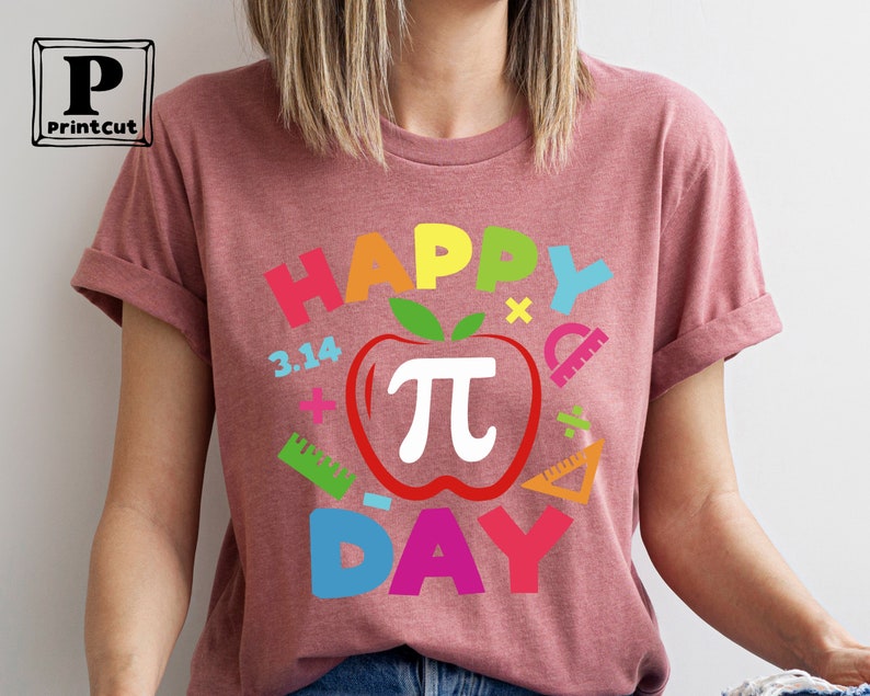 May include: A pink t-shirt with the text "Happy Pi Day" in rainbow colors. The design includes a red apple with a white pi symbol and other math-related symbols.