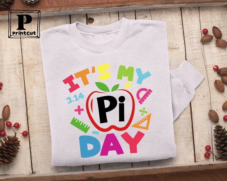 May include: White sweatshirt with a colorful graphic design that says "It's My Pi Day" with a red apple with a black "Pi" inside and other colorful math symbols.