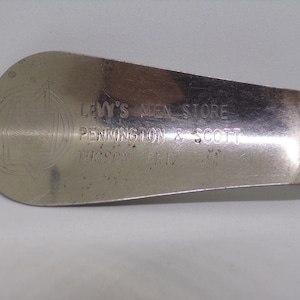 May include: A silver shoehorn with the text "LEVY'S MEN STORE PENNINGTON & SCOTT TUCSON ARIZ." engraved on it.