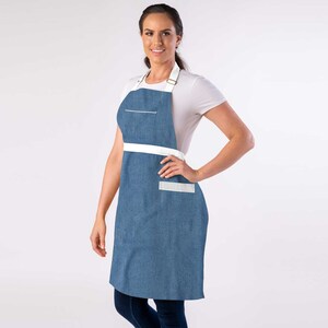 May include: A blue denim apron with white straps and a white pocket. The apron has a white stripe across the waist.