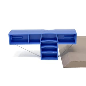 Può includere: Uno strumento di plastica blu a forma di T, utilizzato per segnare e tagliare il cartone. Lo strumento è posizionato su un pezzo di cartone marrone.