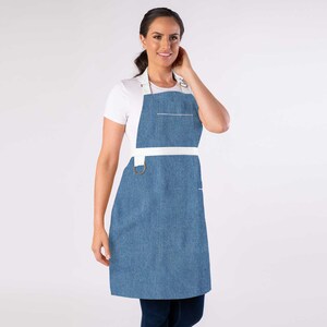 May include: A blue denim apron with white straps and a white pocket. The apron has a metal ring on the strap.