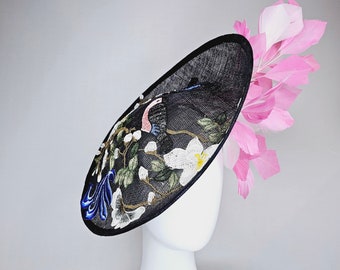 May include: A black fascinator hat with a floral design and pink feathers. The hat is decorated with blue, white, and green embroidery.