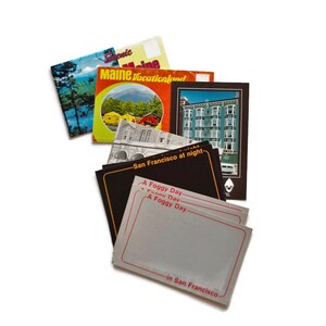 May include: A collection of vintage postcards featuring scenic views and travel destinations. The postcards showcase images of landscapes, buildings, and text that reads "Maine Vacationland", "San Francisco at night", and "A Foggy Day in San Francisco".