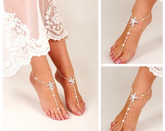 Op de afbeelding: Een paar zilveren blotevoetsandalen met een zeester-ontwerp. De sandalen zijn versierd met strass steentjes en kralen.